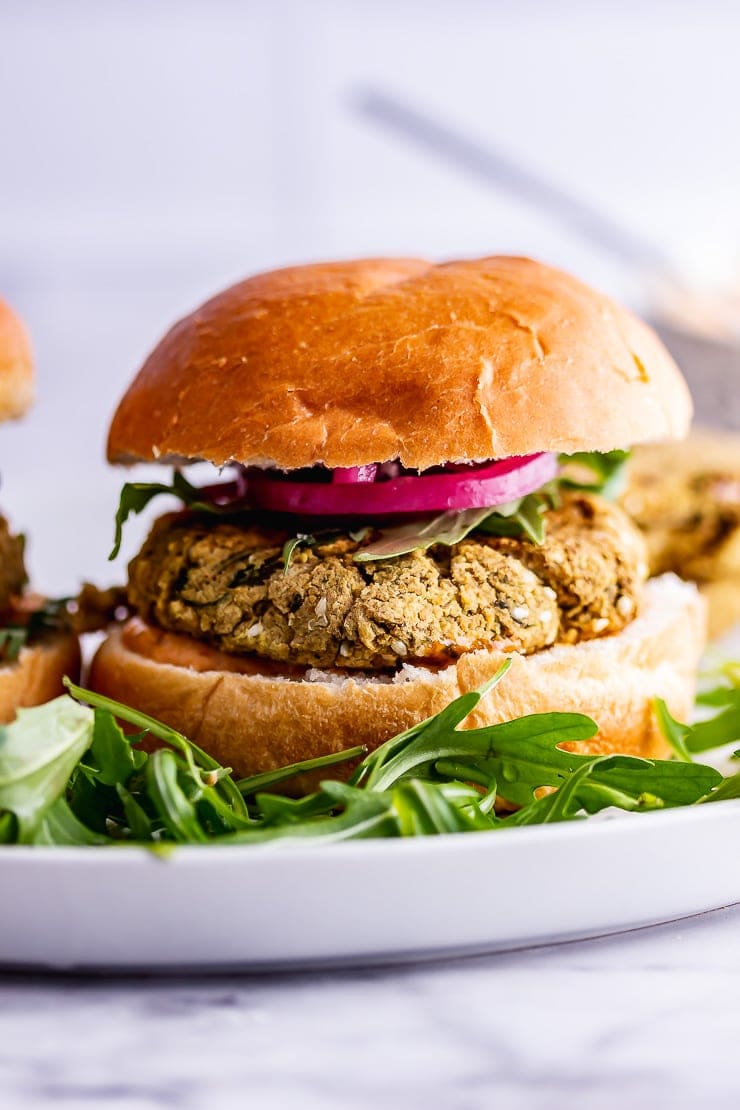 Side on shot of baked falafel burger with rocket and pickled onions