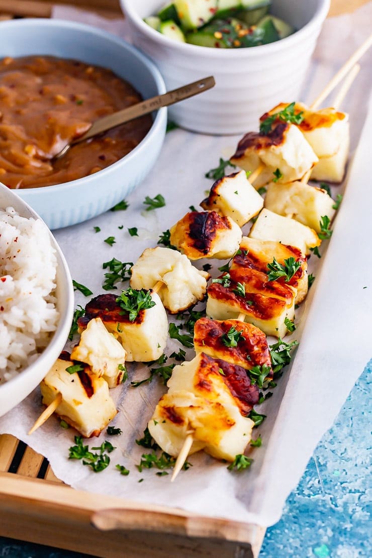 Close up of halloumi skewers on a wooden tray over a blue background