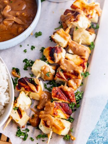 Grilled halloumi skewers drizzled with peanut sauce and fresh herbs