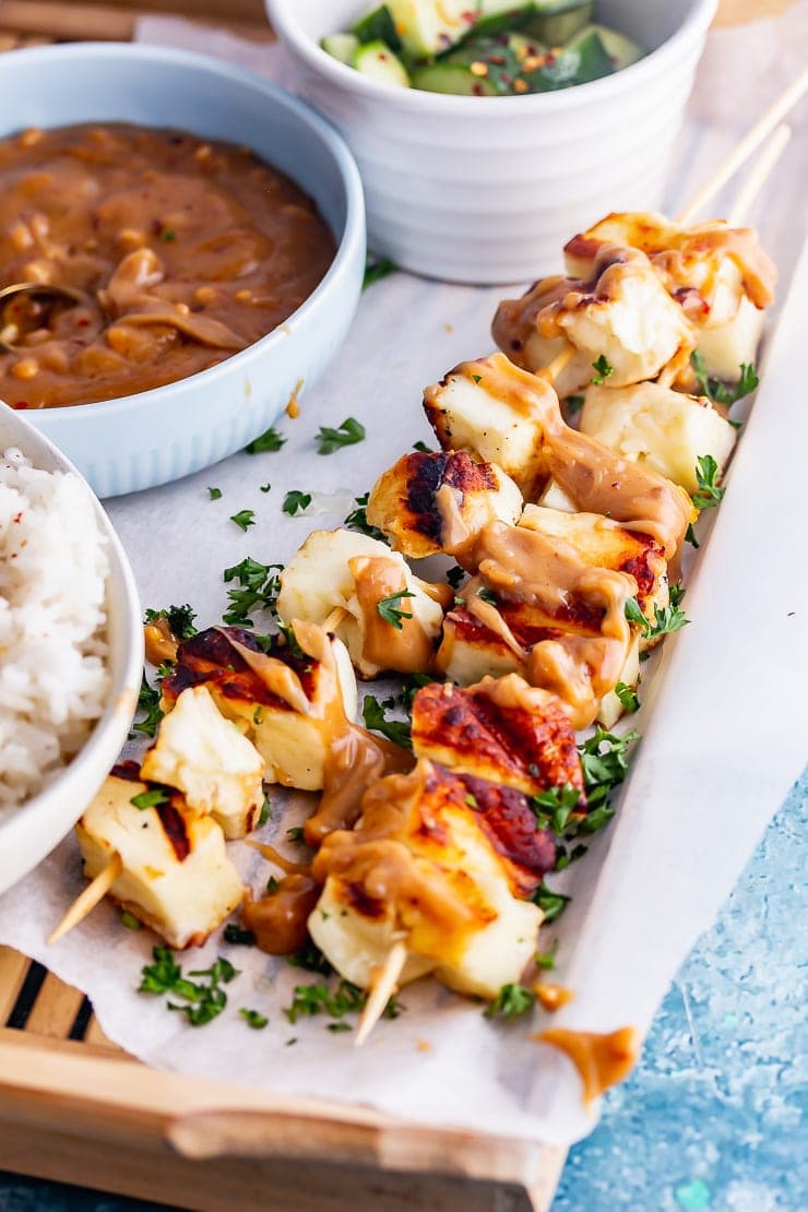 Grilled halloumi skewers in a wooden tray with herbs