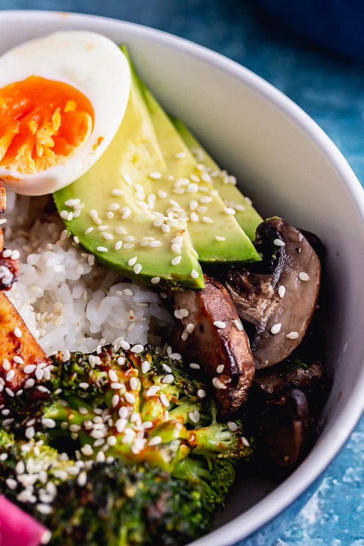 Close up of mushroom and avocado in a baked tofu rice bowl