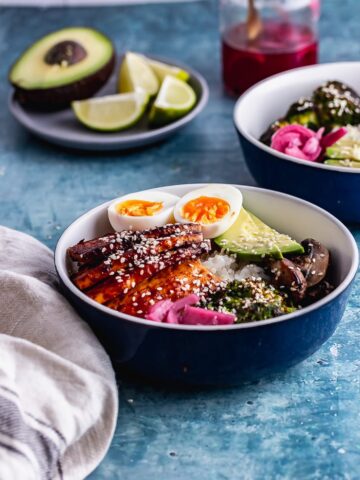 Side on shot of Korean baked tofu rice bowls in a blue bowl with avocado