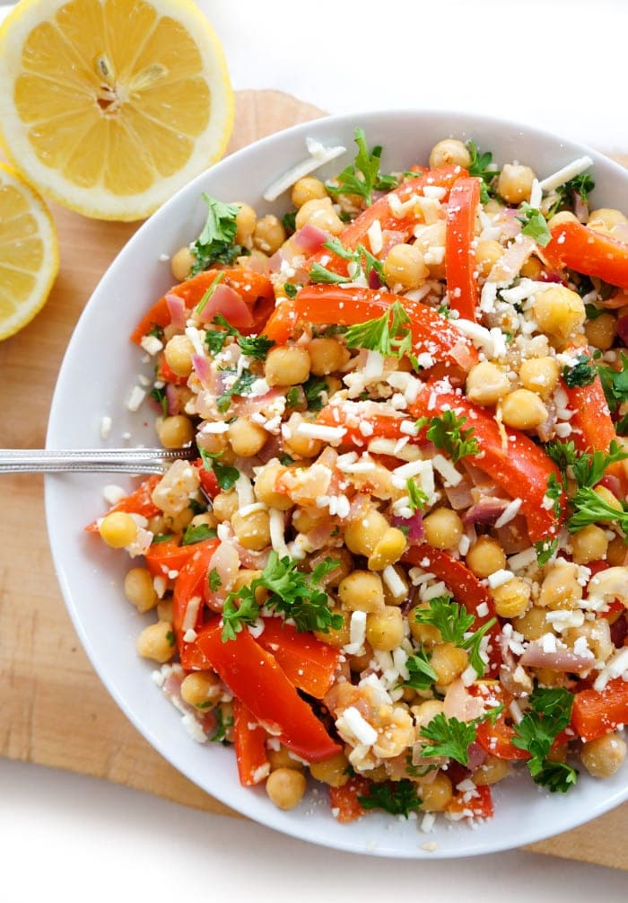 Overhead shot of Mediterranean chickpea salad in a white bowl with lemon