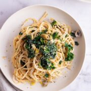 Overhead shot of garlic spaghetti with kale on a marble background