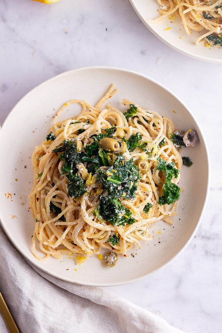 Overhead shot of garlic spaghetti with kale on a marble background