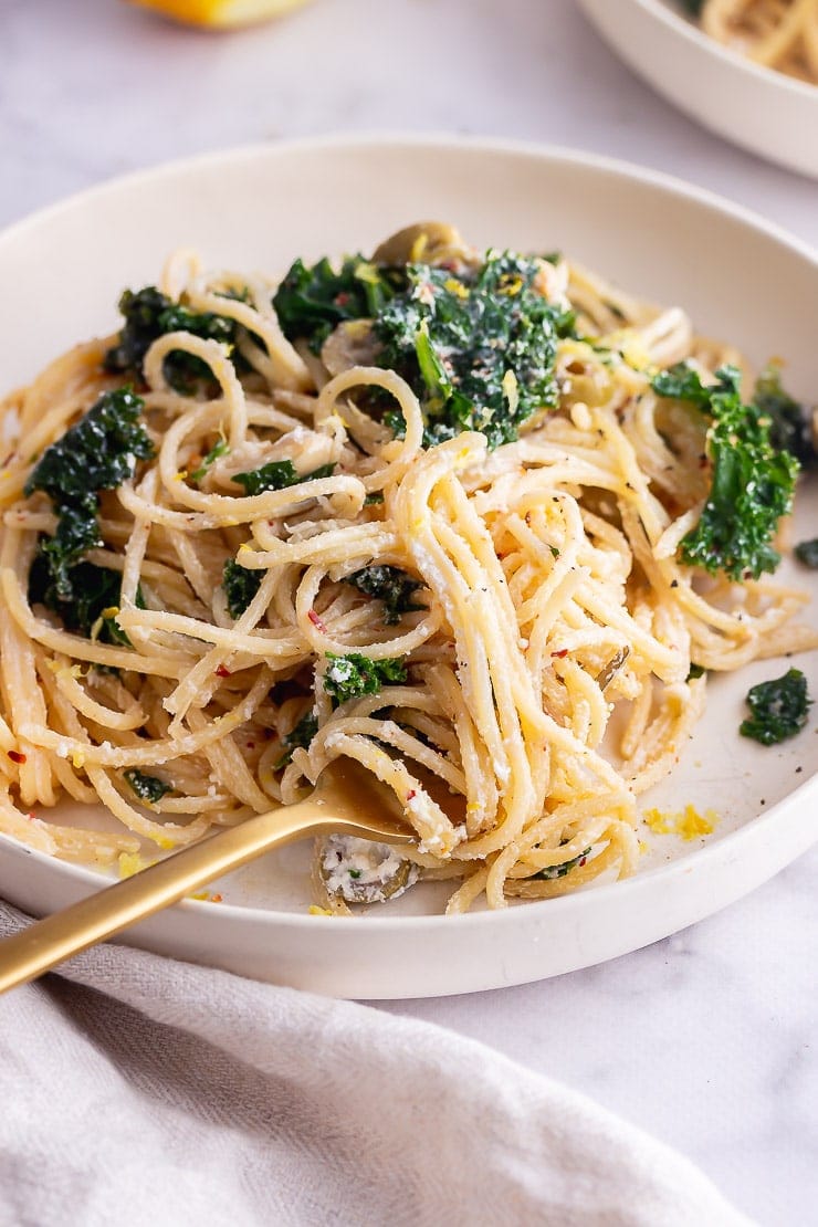 Gold fork with garlic spaghetti in a white bowl