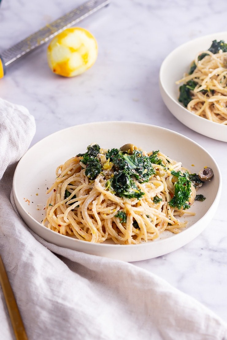 Two bowls of roasted garlic spaghetti on a marble background