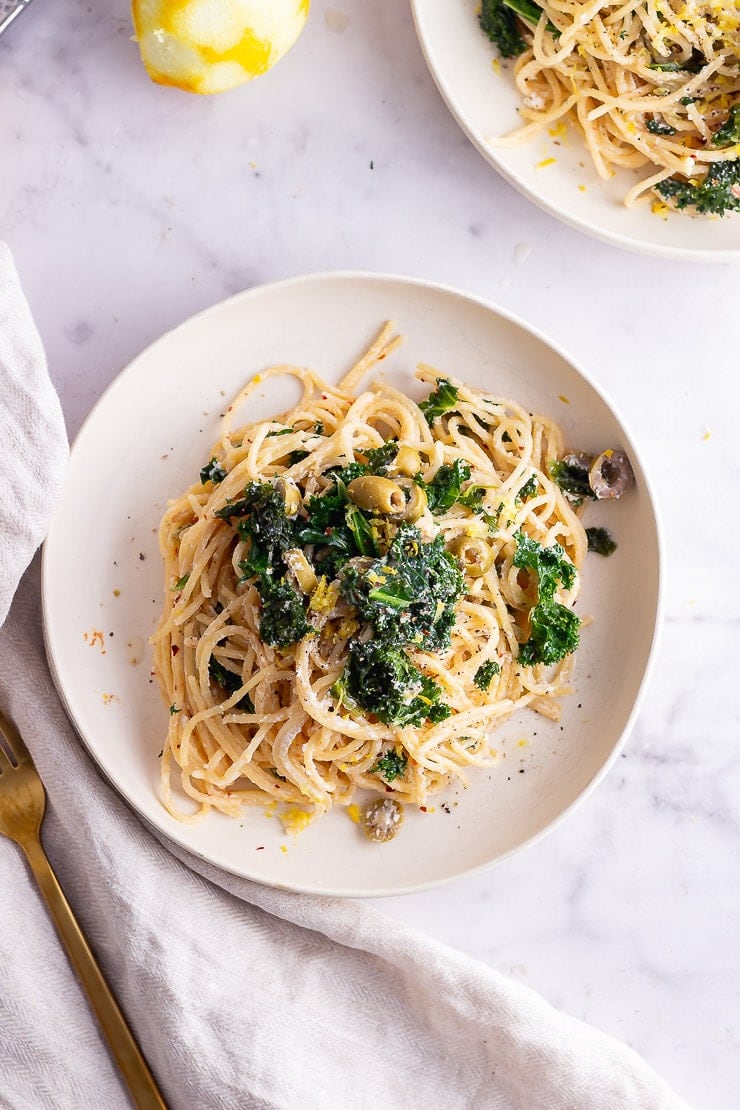 Overhead shot of garlic spaghetti with kale on a marble surface