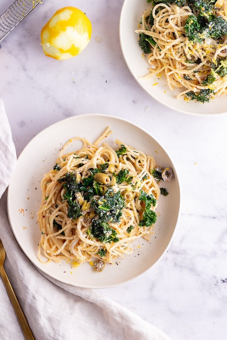 Overhead shot of two bowls of garlic spaghetti with kale and lemon