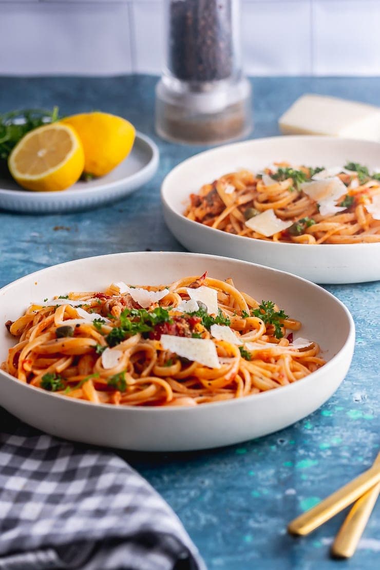 Side on shot of salmon linguine in white bowls on a blue surface