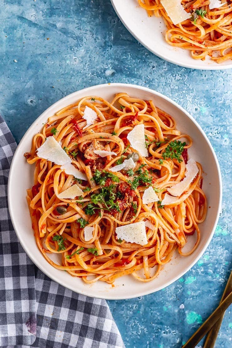 Overhead shot of spicy salmon linguine in a white bowl on a blue background