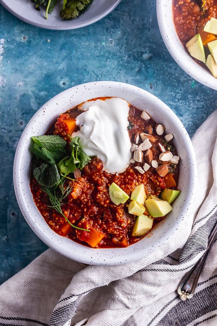 Overhead shot of spicy veggie stew with quinoa on a blue background