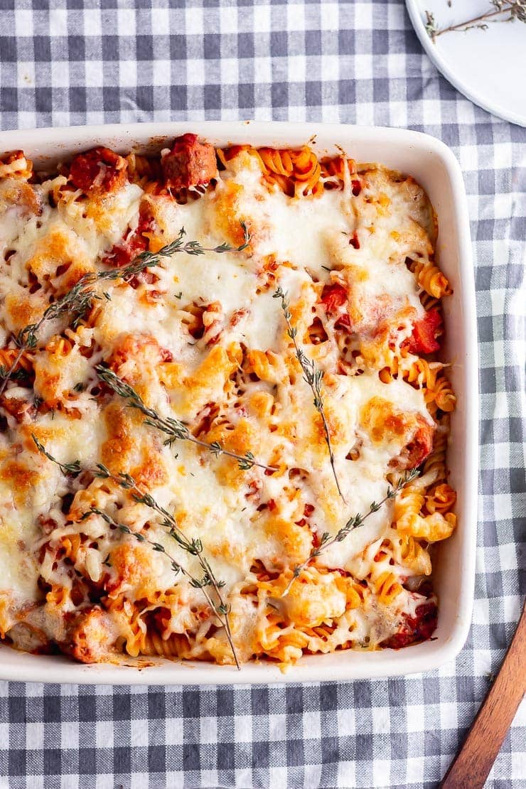 Overhead shot of vegetarian sausage pasta bake on a grey checked cloth