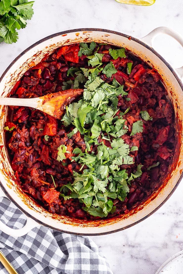 Overhead shot of a cream pot of bean chilli on a marble background