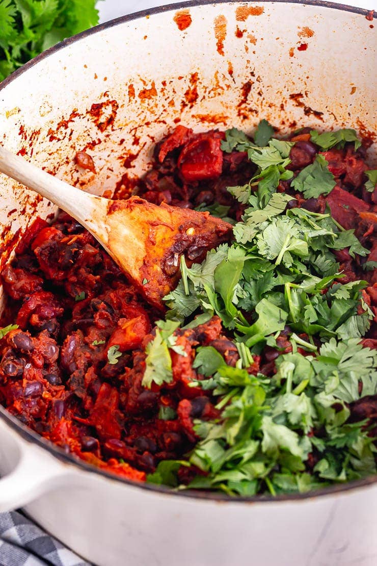 Close up of bean chilli in a white pot with chopped herbs