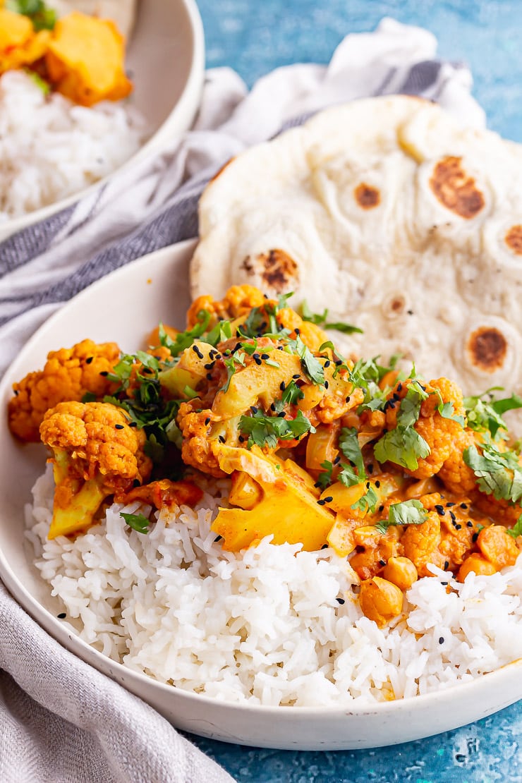 Close up of cauliflower and chickpea curry with rice in a white bowl