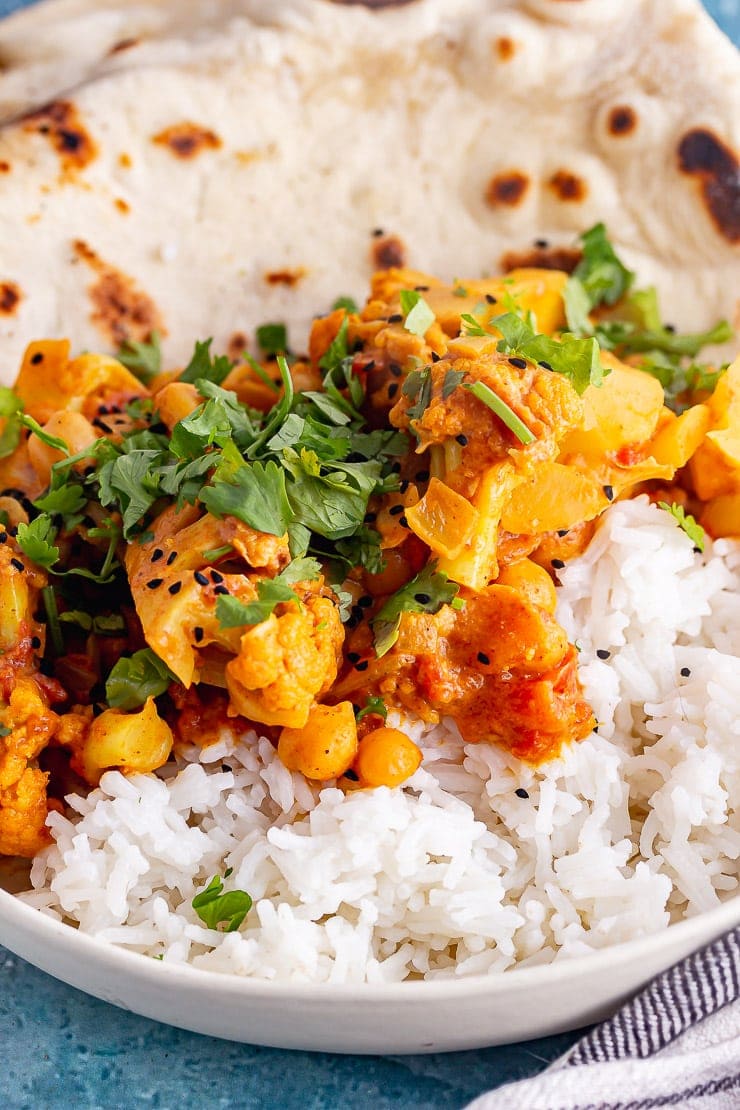 Close up of cauliflower and chickpea curry with rice in a white bowl