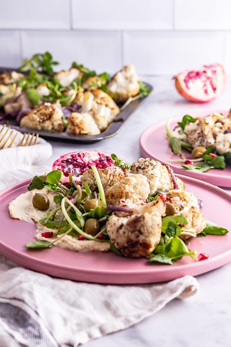 Side on shot of cauliflower salad on a pink plate on a beige cloth