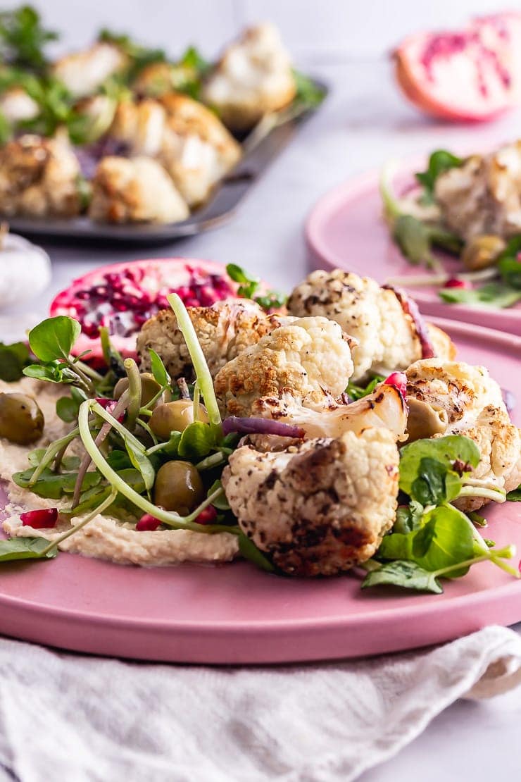 Close up of cauliflower salad with greens on a pink plate