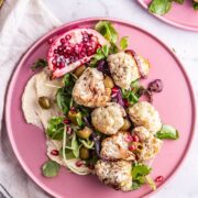 Overhead shot of cauliflower salad on a pink plate on a marble surface