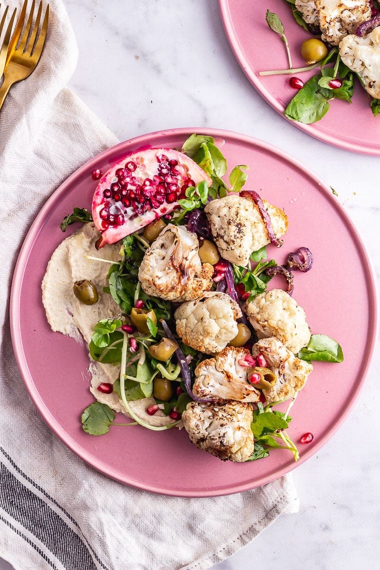 Overhead shot of cauliflower salad on a pink plate on a marble surface