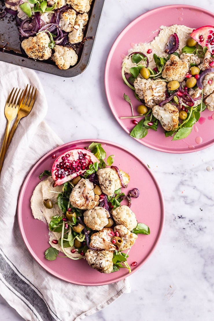 Overhead shot of two plates of cauliflower salad on a marble background