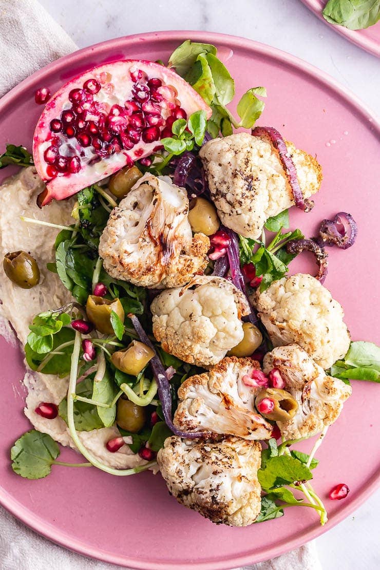 Overhead shot of cauliflower salad with pomegranate and greens