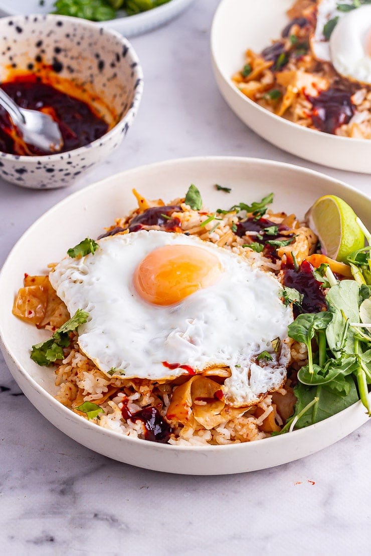 Cream bowl od kimchi fried rice with a fried egg and greens