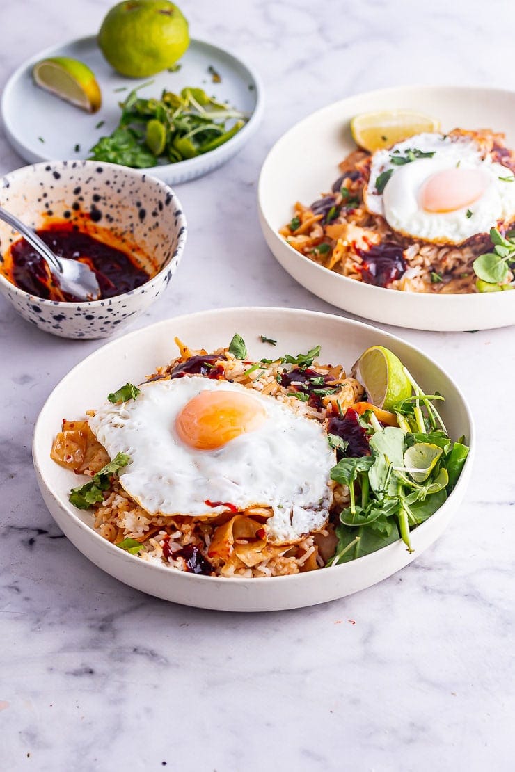 Two bowls of kimchi fried rice topped with fried eggs and gochujang