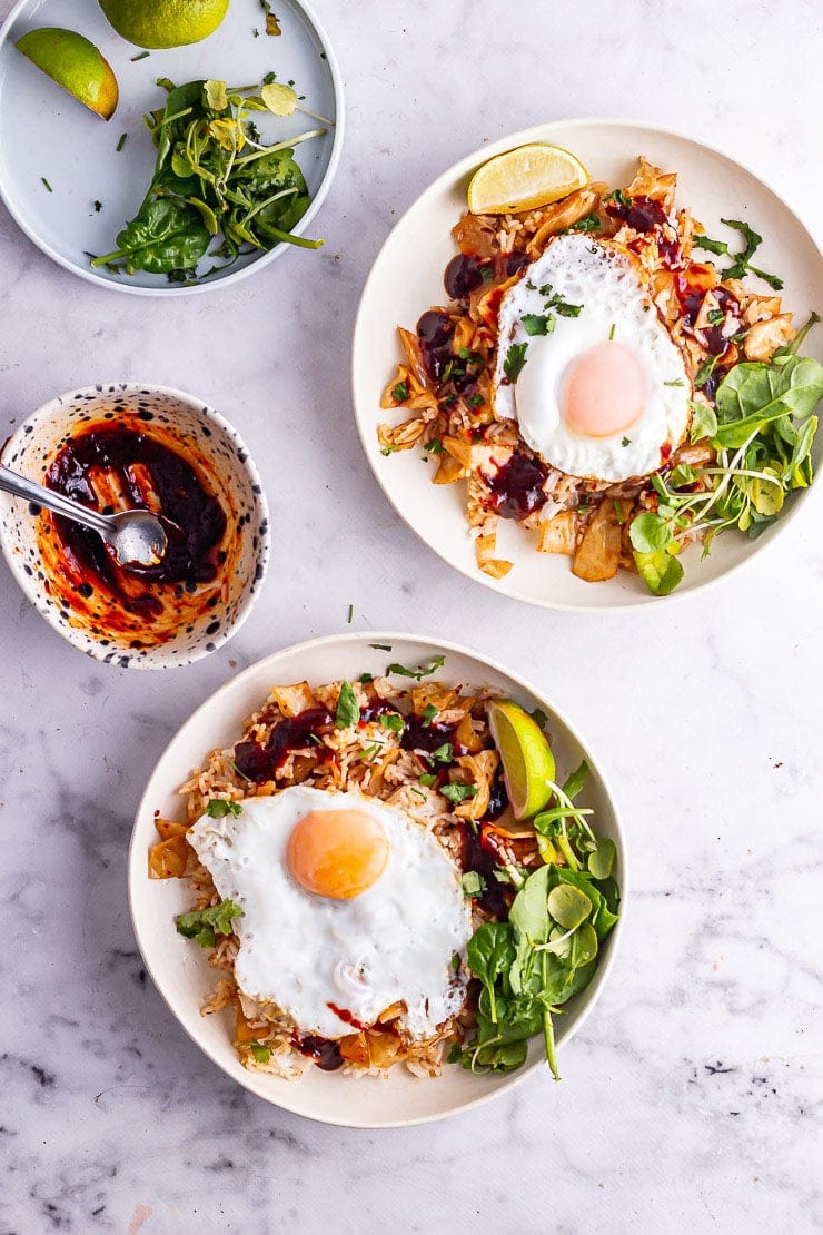 Overhead shot of two bowls of kimchi fried rice on a marble background