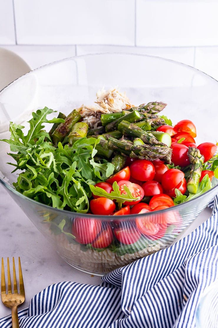 Mackerel pasta salad in a glass bowl with a striped cloth