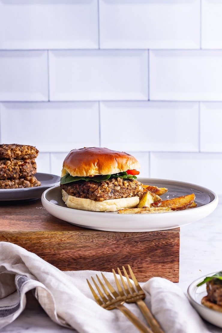 Side on shot of mushroom burgers on a grey plate in front of a white wall