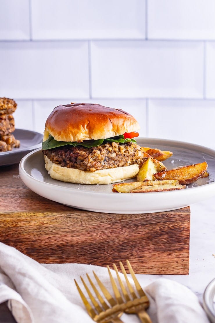 Side shot of a mushroom burger on a grey plate on a wooden box