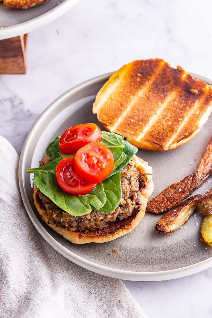 Overhead shot of mushroom burger with spinach and tomato on a grey plate