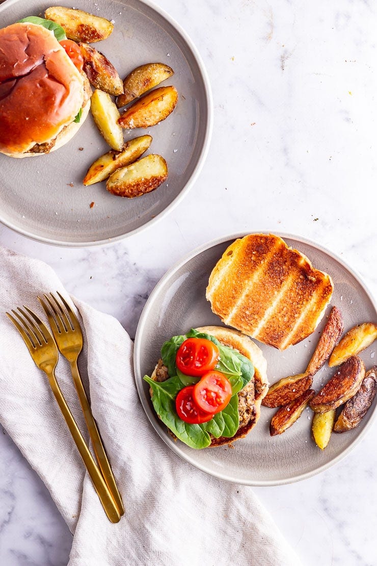 Overhead shot of two plates of mushroom burgers with chips on a marble surface