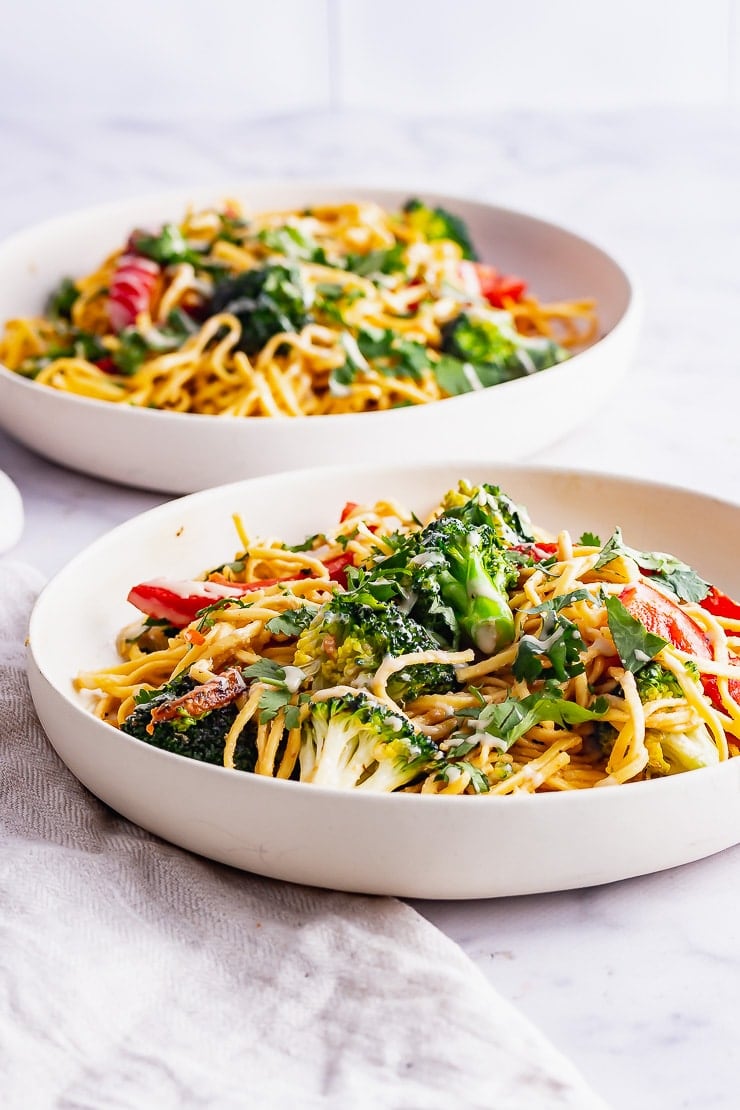 Side on shot of bowls of noodles and vegetables with a beige cloth