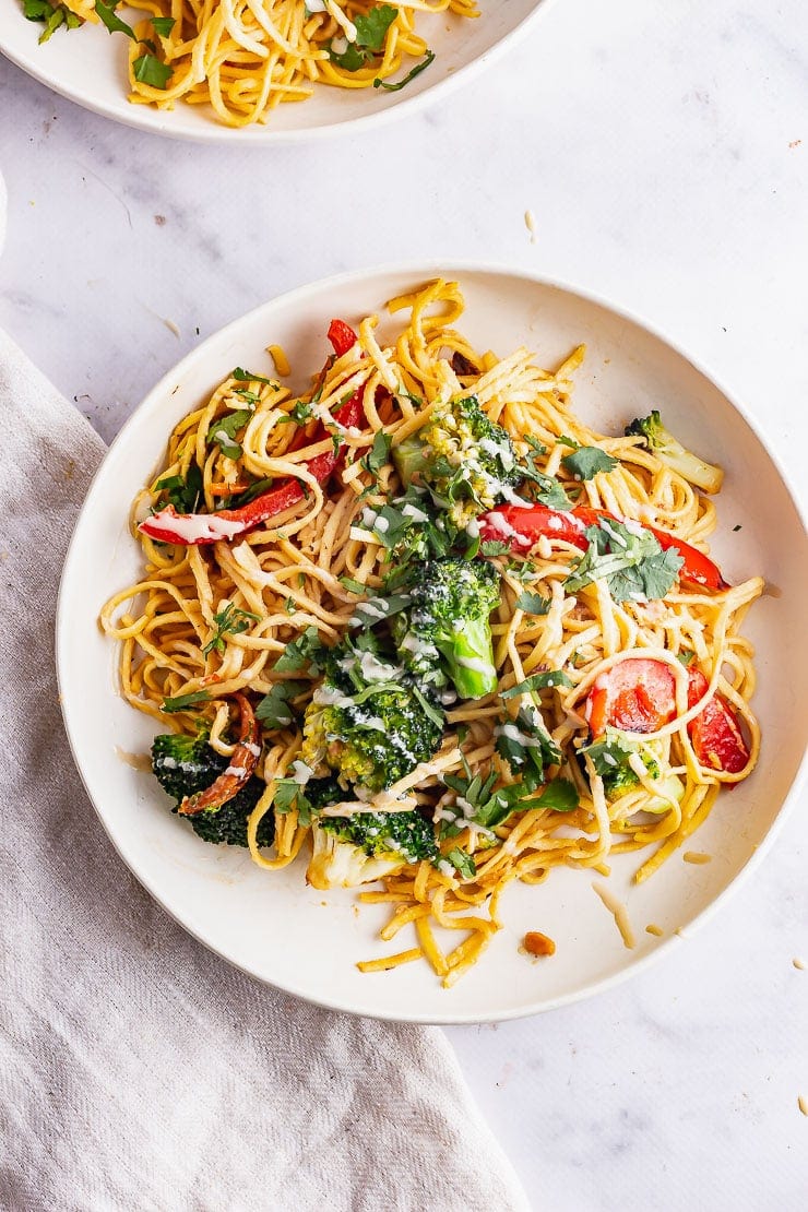 Overhead shot of white bowl of noodle salad on a marble background