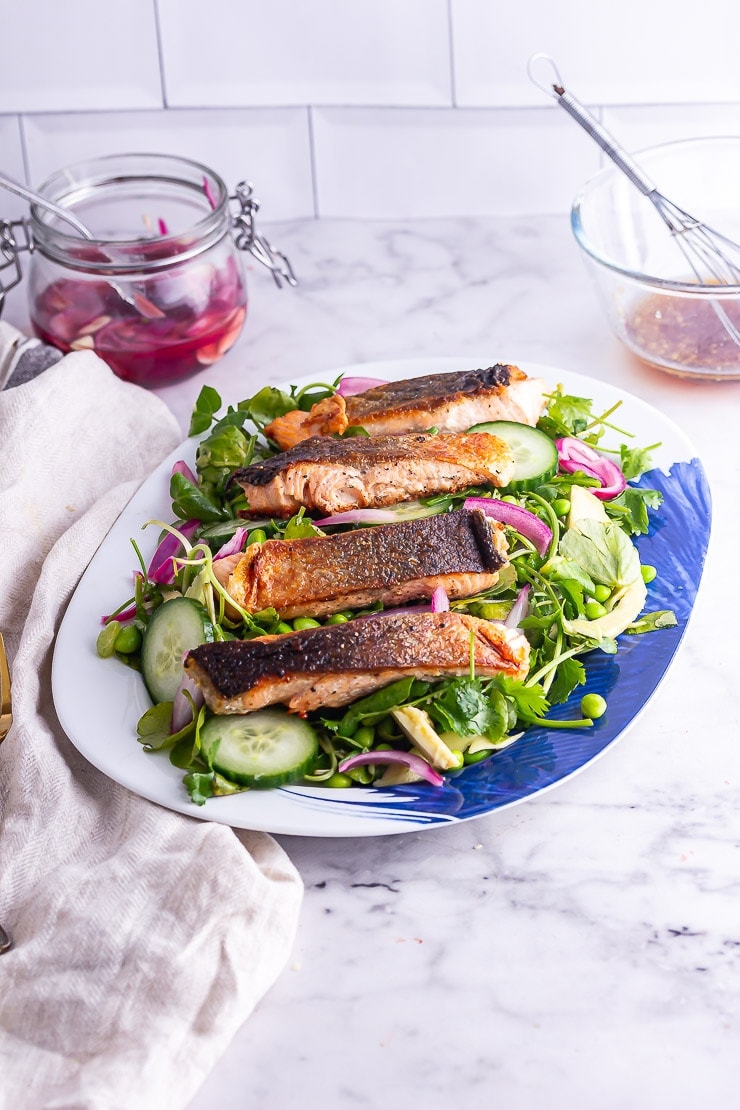 Salmon salad on a platter in front of a white brick wall