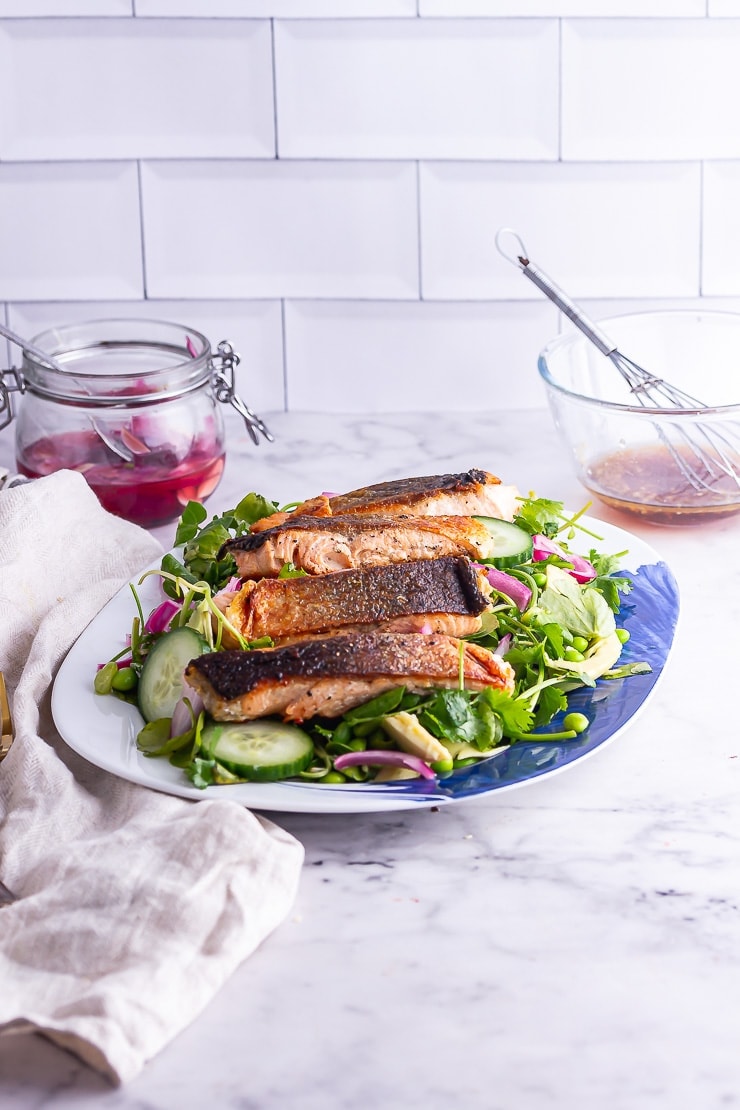 Side on shot of salmon salad on a blue platter with dressing in the background