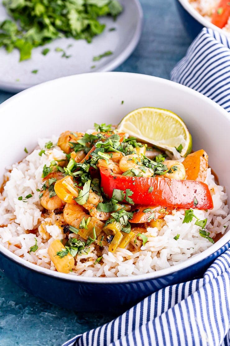 Blue bowl of Thai prawn curry with rice and lime