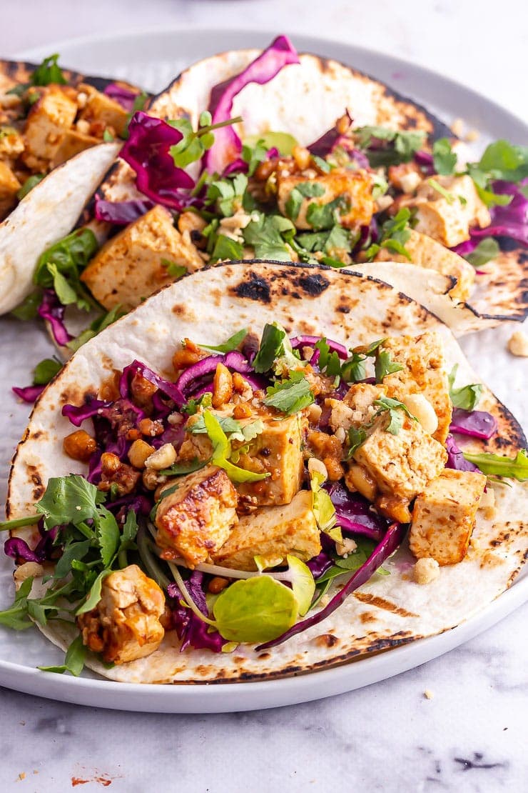 Peanut tofu tacos with cabbage slaw and coriander on a grey platter