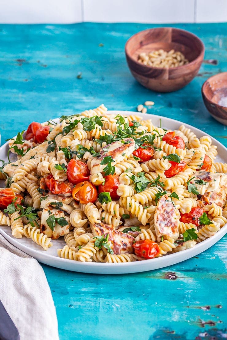 Halloumi pasta with tomato and parsley on a blue background