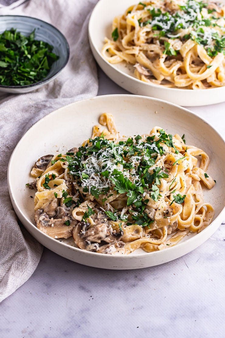 White bowl of mushroom tagliatelle on a marble background