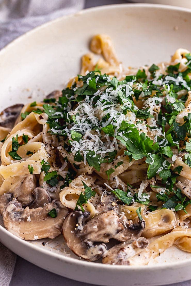 Close up of mushroom tagliatelle with parsley in a cream bowl