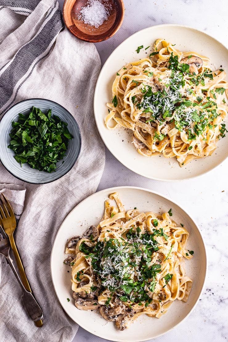 Overhead shot of pasta in white bowls on a marble surface