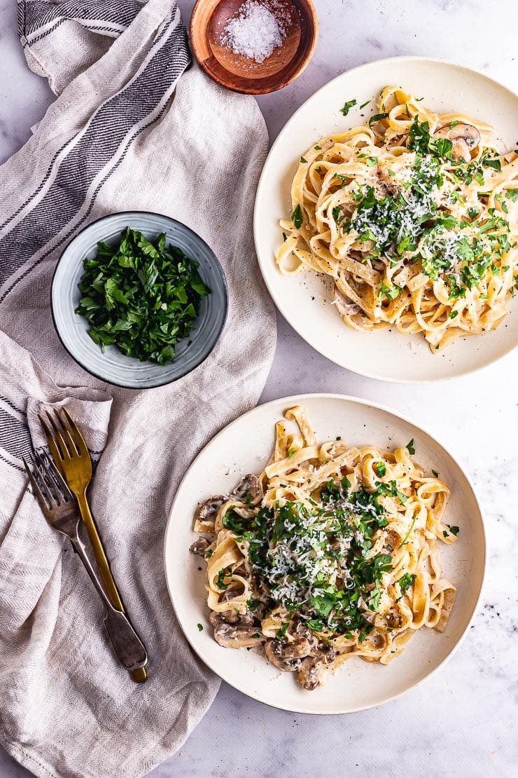 Two bowls of food on a msrble background with cutlery and other ingredients