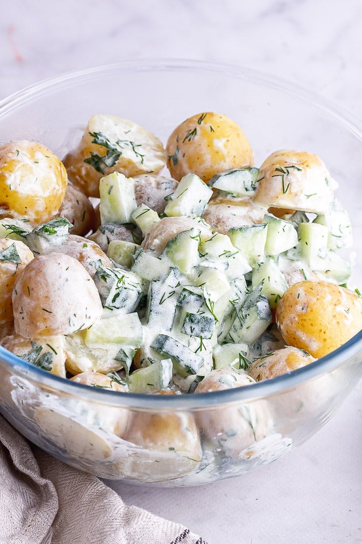 Close up of healthy potato salad in a glass bowl on a marble surface