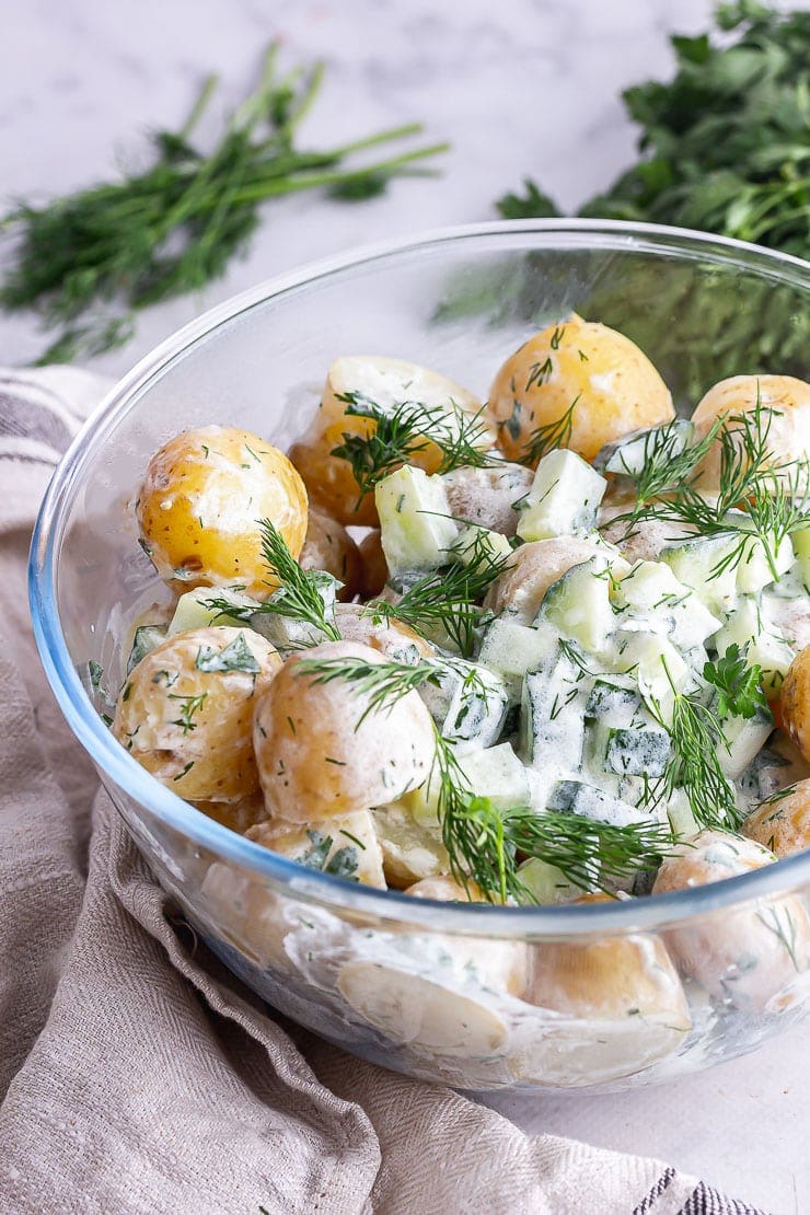 Close up of a glass bowl of healthy potato salad with a cream cloth