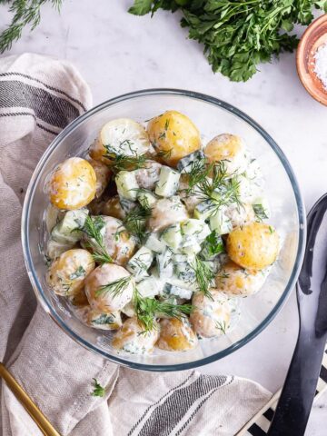 Overhead shot of healthy potato salad on a marble background with salt and herbs