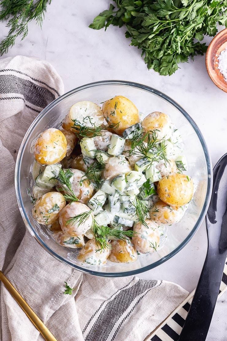 Overhead shot of healthy potato salad on a marble background with salt and herbs